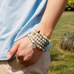 Load image into Gallery viewer, Empowerment by Lotus Flower 108 Beads Mala Wear as bracelet by man model in garden
